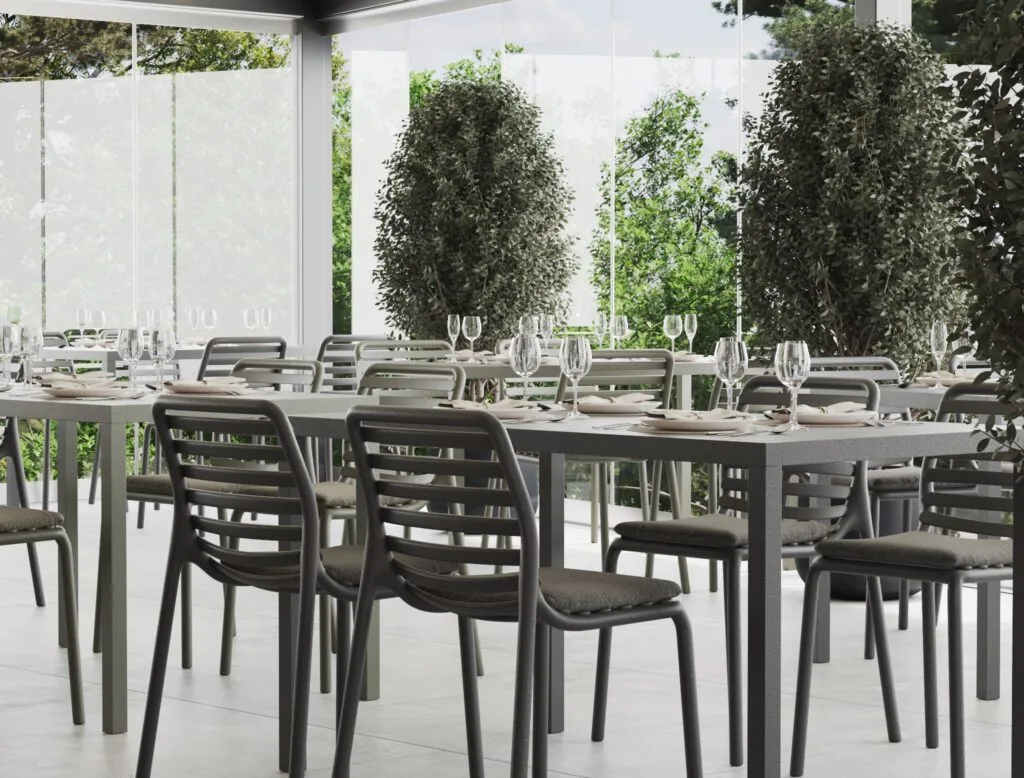 Outdoor terrace dining with black chairs and glass surroundings - Intervibe Studio