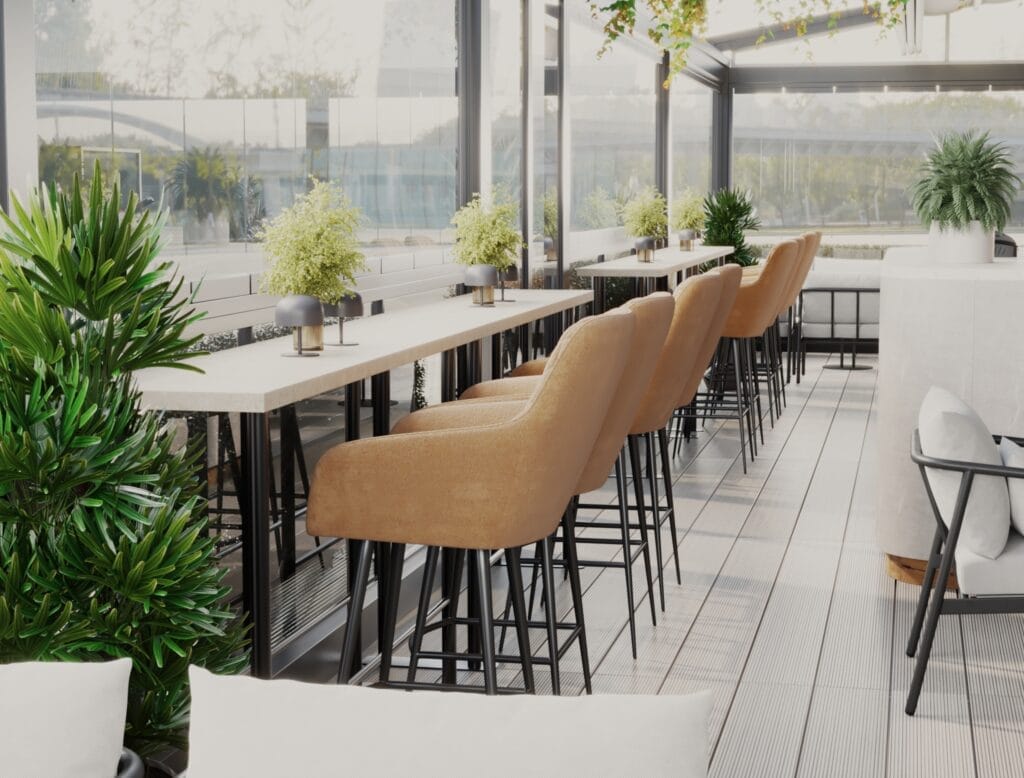 Outdoor café terrace with high bar table, mustard-colored bar stools, and greenery