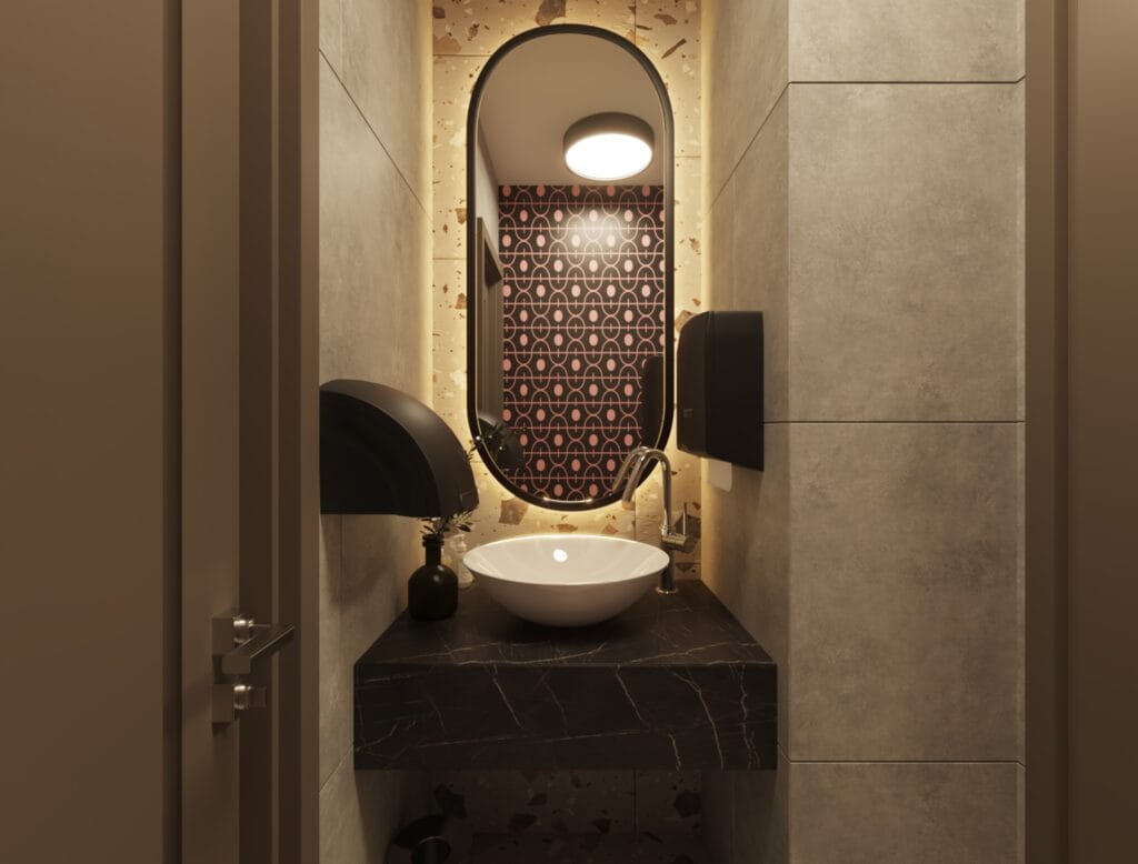 Women’s restroom vanity with terrazzo wall tiles, oval mirror, and round sink basin