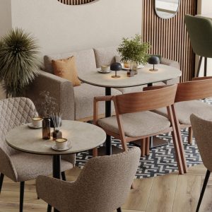 Café seating area with round marble tables, wooden chairs, and soft beige armchairs
