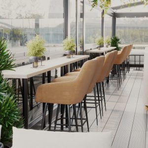 Outdoor café terrace with high bar table, mustard-colored bar stools, and greenery